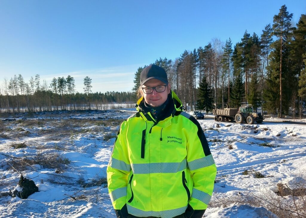 Kauhavan kaupungin maankäyttöasiantuntija Aleksi Saukko valvoo Saarijärven ruoppausta. Taustalla Noorinmäen läjitysalue järven läheisyydessä.