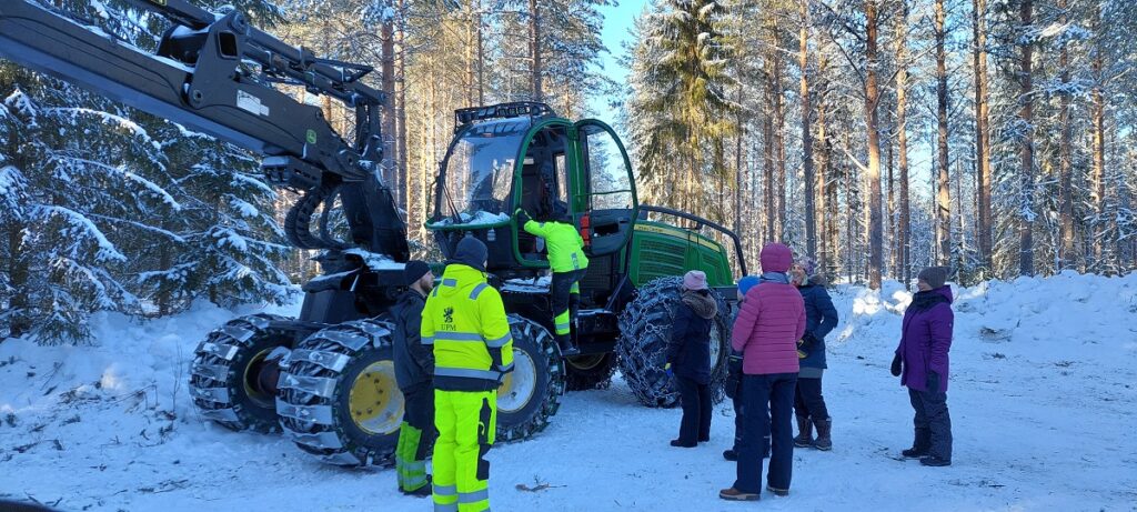 Metsäkone kiinnosti myös aikuisia. Vasemmalta Eemil Granvik, Daniel Lillstrang, koneeseen kiipeämässä Veeti Lassila. Vuoroaan odottavat Ana Thimasirithanatcha ja Santeri Kellokoski. Oikealla koulun henkilökunnasta koulunkäyntiavustaja Soile Söderling, koulun johtaja Virpi Mäkelä ja selin opettaja Kirsi-Marja Perkkalainen.