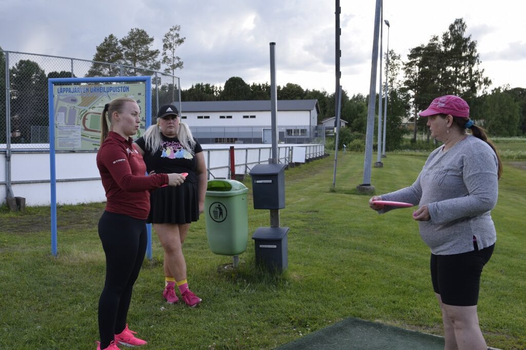 Jenni Keronen (vasemmalla) opastaa Sirpa Korkeasaarta heittotekniikassa. JSDC:n Karoliina Pitkäaho tarkkailee taustalla.