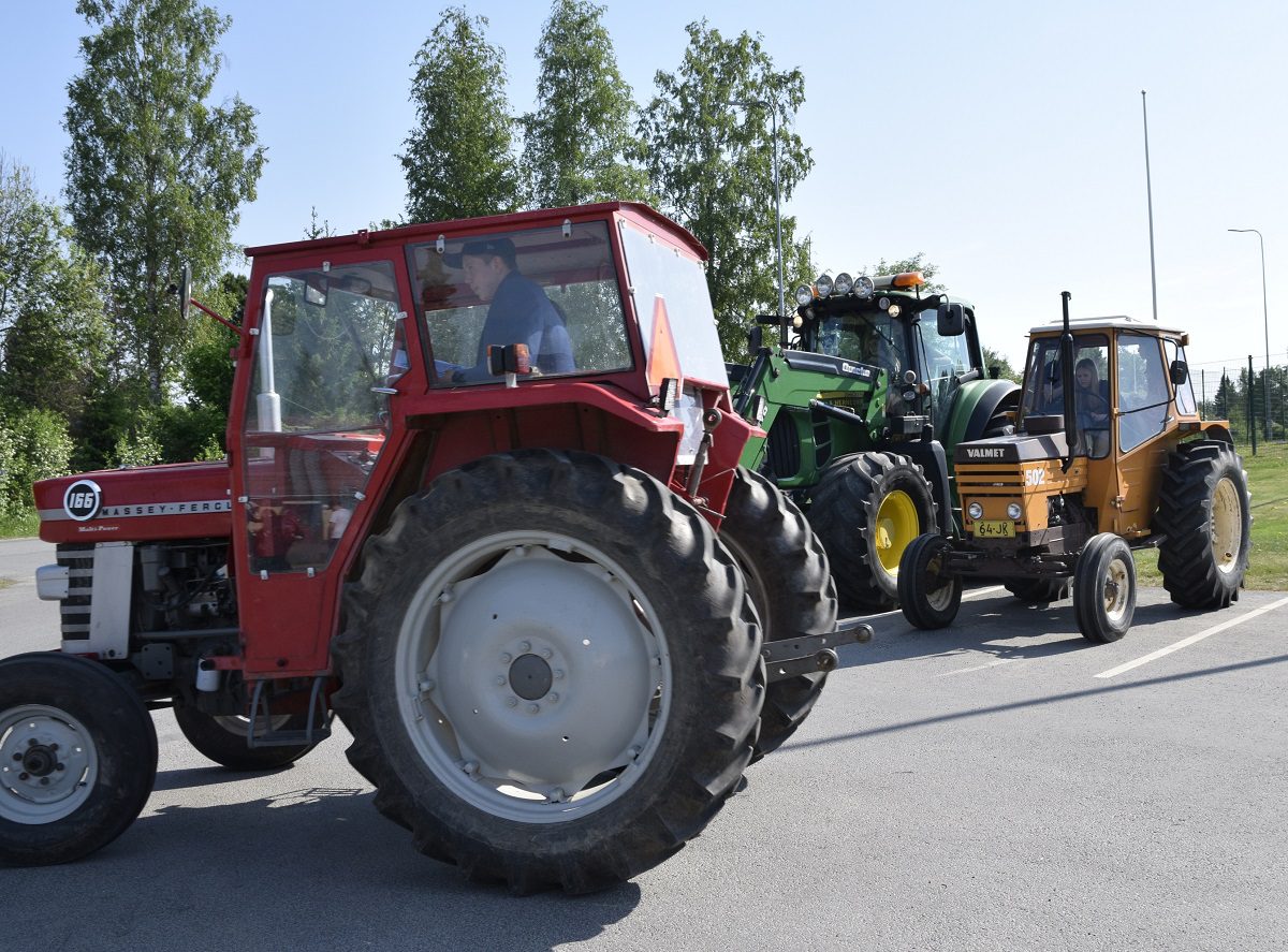 Marssille osallistuneet kolme traktorillista nuoria lähtivät koulun pihasta ansaitulle kesälomalle kylän raitin kautta.