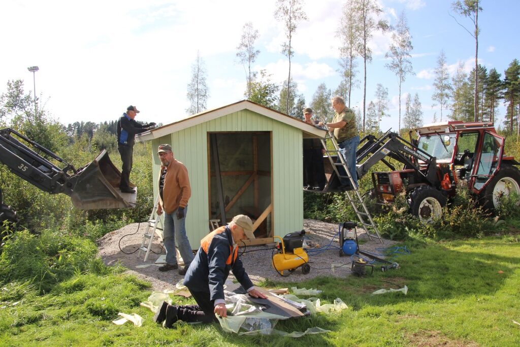 Talkoomiehet Jaakko Kontiainen (vas.), Lasse Kari, Vesa Pellinen, Erkki Peltotupa ja Esko Pellinen asentavat palahuopaa rakennuksen katteeksi.