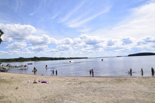 Aurinkoinen, lämmin sää oli houkutellut Lappajärven Nykälänniemen rannalle väkeä. Rannalta löytyy pukukopit, läheisyydestä ravintolapalvelut ja muun muassa polkuveneen vuokrausta. Vesijetit olivat kuvauspäivänä rantautuneet hiekalle.